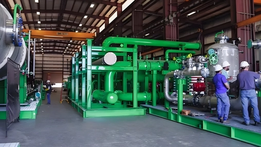 Workers inspecting green hydrogen processing equipment inside an industrial facility